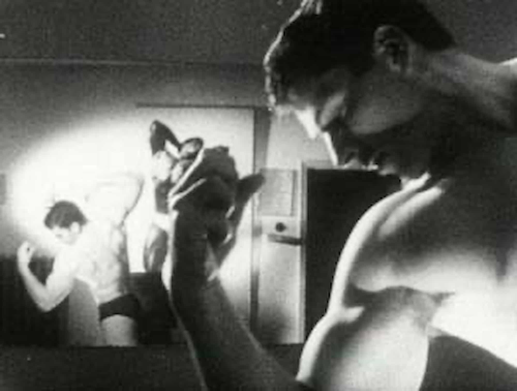 Prizor iz filma. Vidimo mišičastega moškega, ki gleda v svoje napete bicepse.